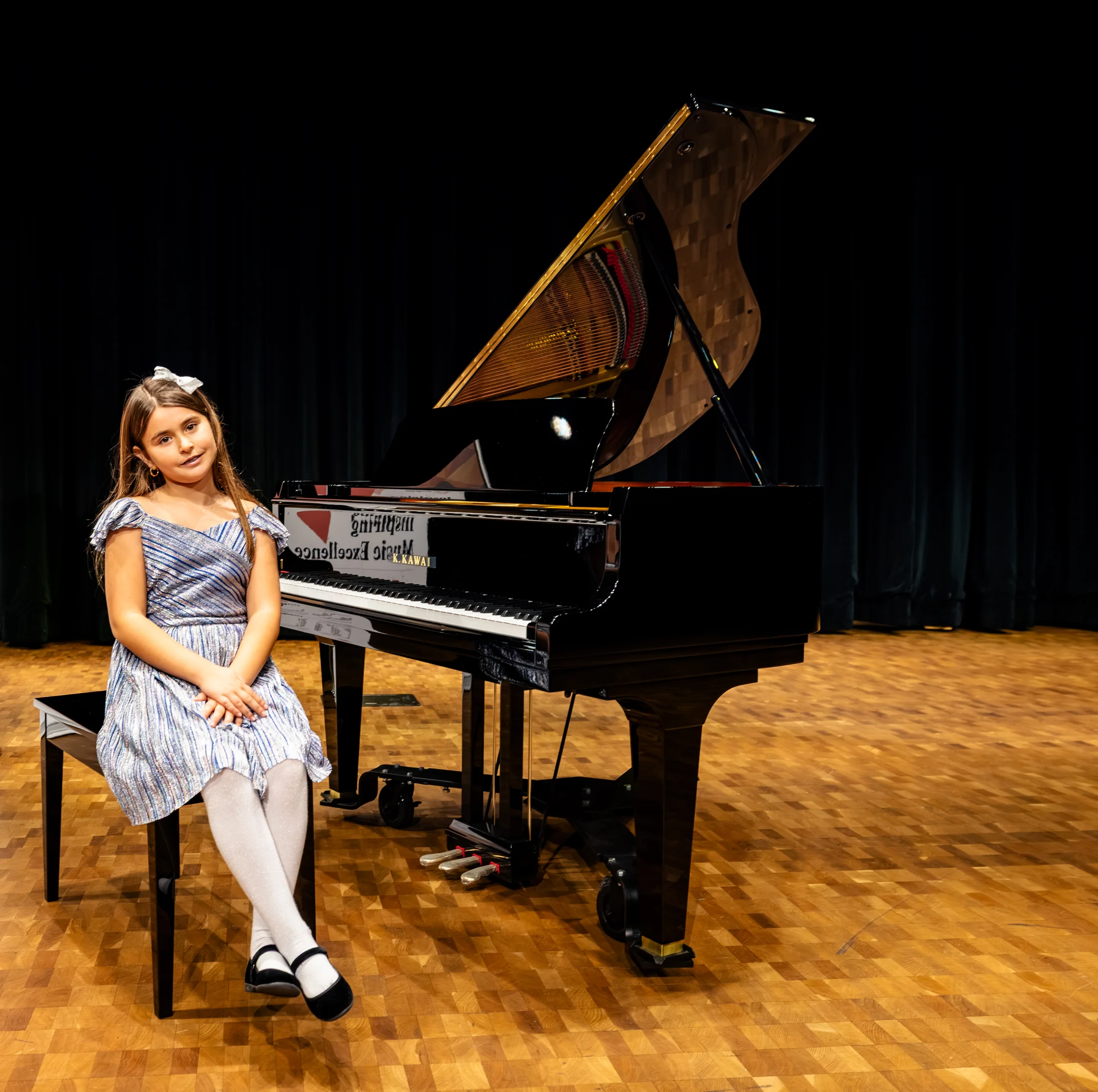 An OC Piano Program student seated at the grand piano on the recital stage