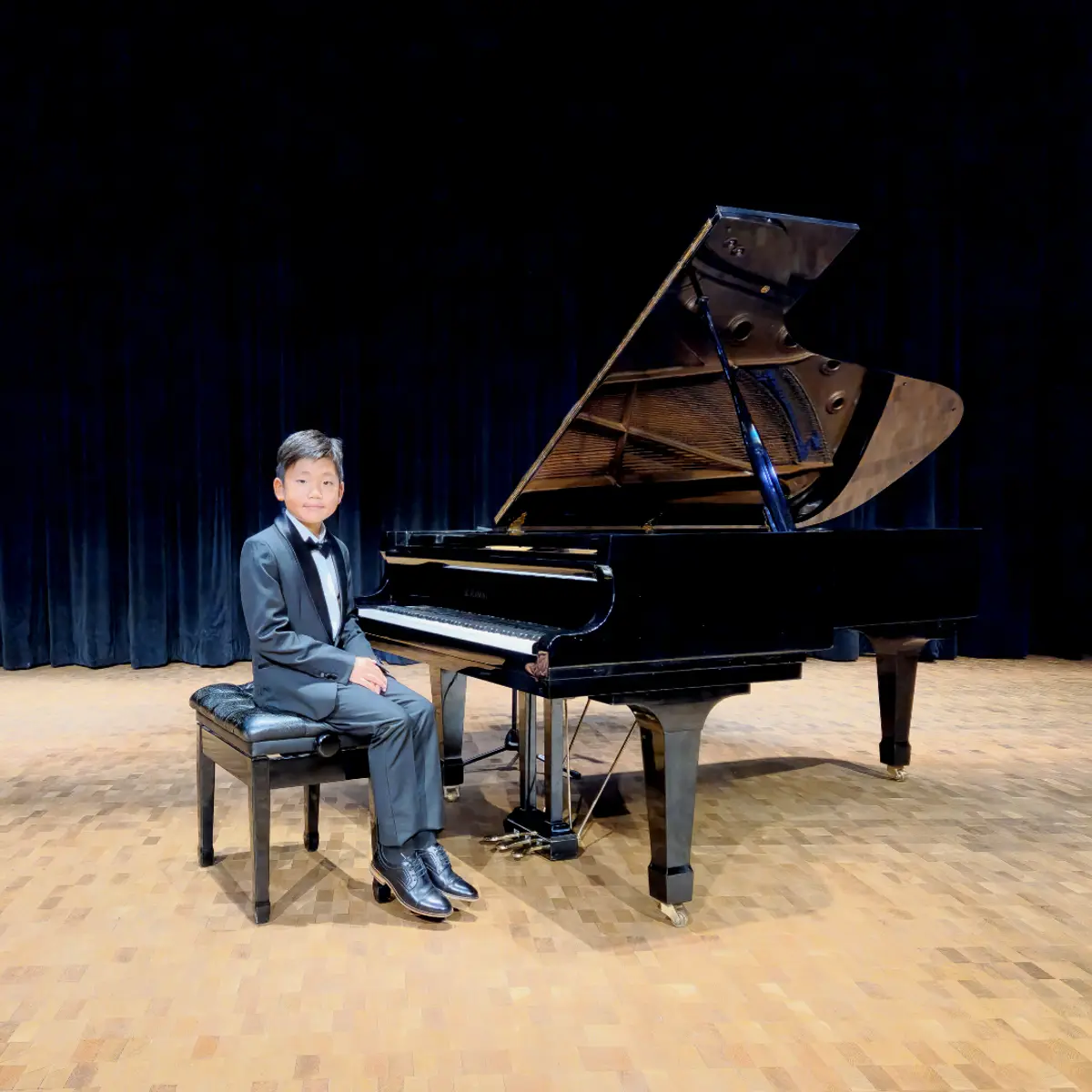An OC Piano Program student seated beside the grand piano at the annual recital